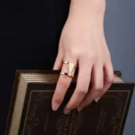 a woman holding a book and wearing the Double Hollow Statement Ring on her finger