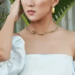 a woman in a white dress wearing golden earrings and the Square Toggle Clasp Golden Chain Necklace