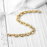 the Breathtaking Golden Coffee Bean Chain Bracelet on a white wooden surface