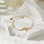 the Exciting Golden Heartbeat Bracelet on a white concrete surface