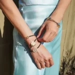 a woman in a blue dress wearing the Gold Love Heart Charm Beaded Bracelet on her arm