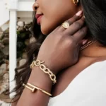 a black woman wearing the Gold Screw Nail Bangle And Wire Link Bracelet Set