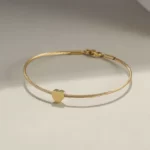 the heart charm of the Golden Heart Cable Bangle Bracelet