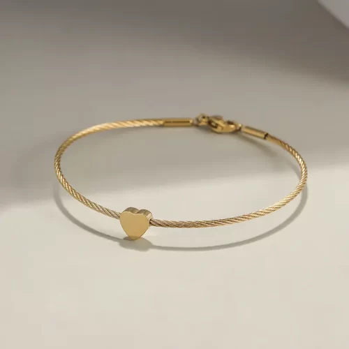 the heart charm of the Golden Heart Cable Bangle Bracelet