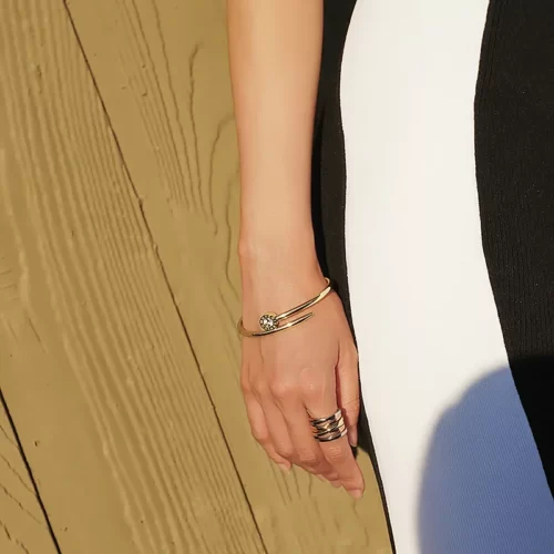 a woman wearing the Mischievous Golden Nail Crossover Bangle on her arm