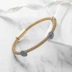 the New Gold Cable Bangle With 3 Turquoise Stations on a white marble surface