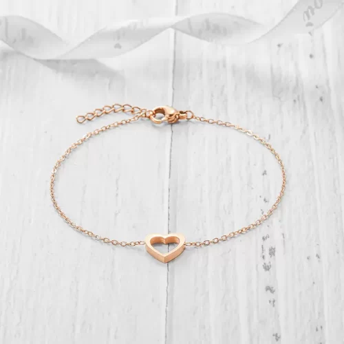 the rose gold Open Heart Charm Bracelet on a white wooden surface