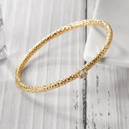 close up photo of the Terrific Golden Hammered Bangle Bracelet on a white wooden surface