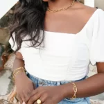 a black woman in a white top wearing the Golden Threader Interlocking Bracelet