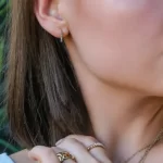 a woman wearing the rainbow earrings of the Starburst Rainbow Hoop Earrings Set