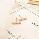 the Adorable Golden Bar CZ Stud Earrings on a piece of paper