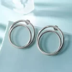 close up photo of the Double Layered Silver Tone Hoop Earrings on a blue background