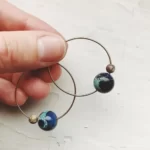 a hand holding the Cosmic Hoop Earrings With Jasper Beads