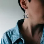 a woman in a jeans shirt wearing the Jupiter and Galilean Moons Dangle Earrings